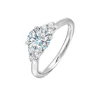 Three stone ring features a trinity of diamonds on either side, focusing the round solitaire at center, is a symbol of everlasting love.
