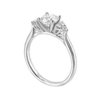 Three stone ring features a trinity of diamonds on either side, focusing the round solitaire at center, is a symbol of everlasting love.